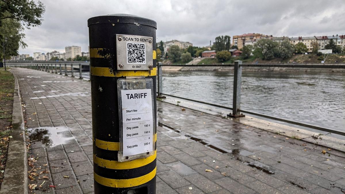 KoloRide rental post with a QR plate and tariff card on the Podil riverside path in Kyiv